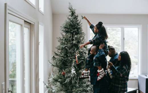 A girl putting a christmas star on a christmas tree