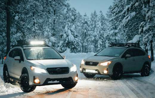 Two white suvs on snow covered road