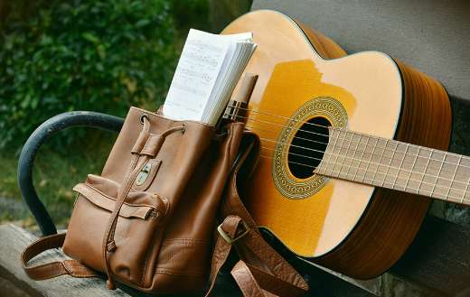 Brown acoustic guitar and brown leather backpack