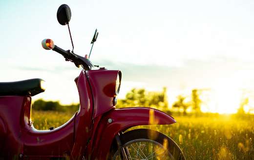 Red scooter on the grass field sunset online