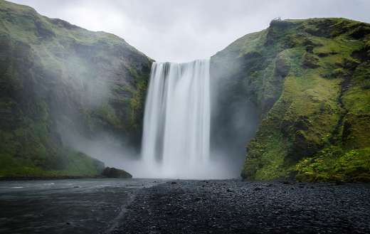Water falls on the green covered mountain during daytime