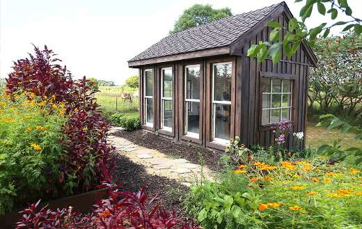 Old wooden gazebo in lush rural cottage garden