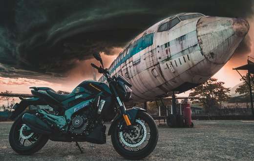 Black motocycle parked next to old airplane